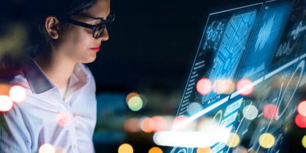 Frau mit Brille blickt auf ein digitales Data Dashboard
